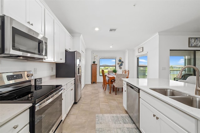 kitchen featuring visible vents, crown molding, appliances with stainless steel finishes, a sink, and a wealth of natural light