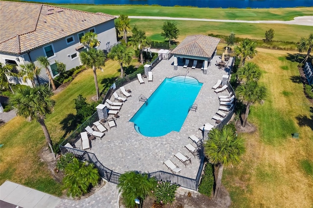 community pool featuring fence, view of golf course, and a water view