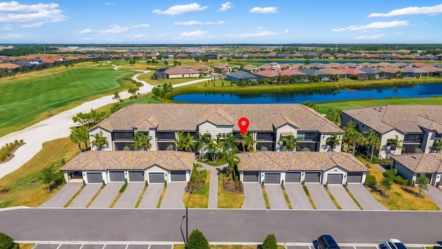 drone / aerial view featuring a water view, view of golf course, and a residential view