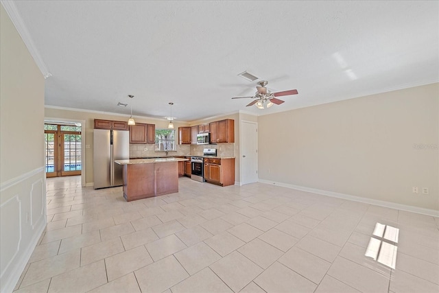 kitchen featuring appliances with stainless steel finishes, open floor plan, a kitchen island, visible vents, and ornamental molding