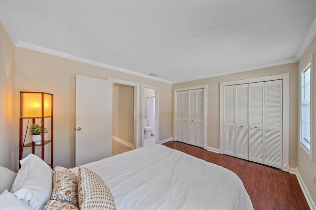 bedroom featuring baseboards, multiple closets, ornamental molding, and wood finished floors