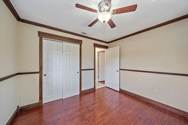unfurnished bedroom with visible vents, baseboards, wood finished floors, and a closet