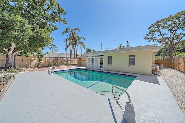view of swimming pool featuring central AC, a patio, a fenced backyard, french doors, and a fenced in pool