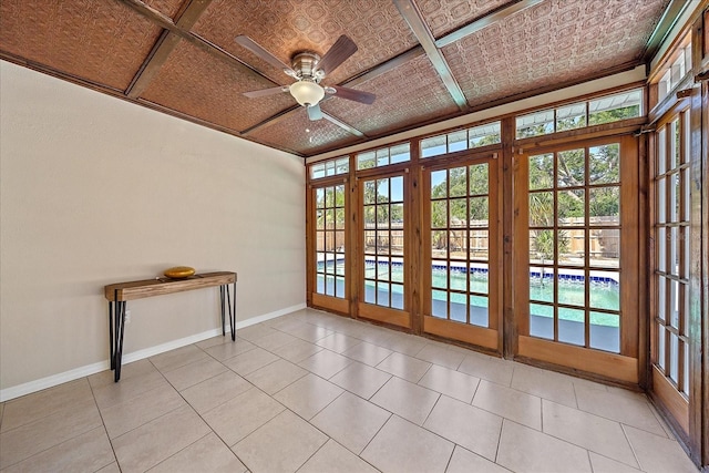 doorway featuring an ornate ceiling, light tile patterned floors, baseboards, and ceiling fan