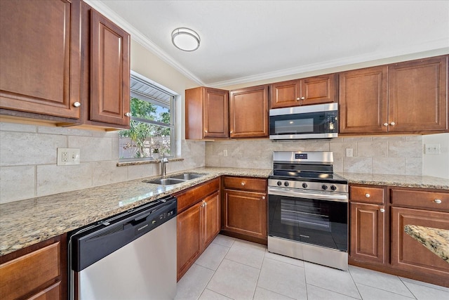 kitchen with crown molding, appliances with stainless steel finishes, light stone counters, a sink, and light tile patterned floors