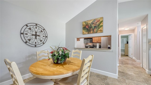 dining area featuring baseboards and lofted ceiling