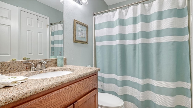 bathroom featuring toilet, curtained shower, vanity, and a textured wall