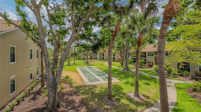 view of property's community with shuffleboard and a lawn