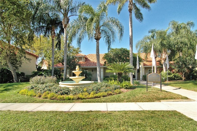 mediterranean / spanish-style home with a front lawn, a tiled roof, and stucco siding