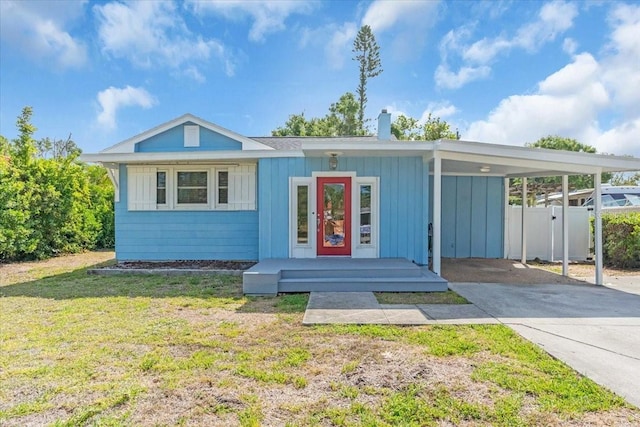 5012 Eastchester Dr, Sarasota, FL 34234 - bungalow-style house with fence, a front yard, a chimney, concrete driveway, and a carport