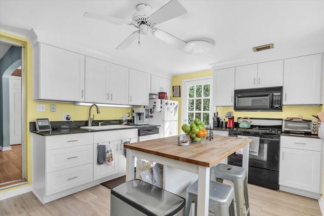 5012 Eastchester Dr, Sarasota, FL 34234 - kitchen with dark countertops, a sink, white cabinetry, a ceiling fan, and black appliances