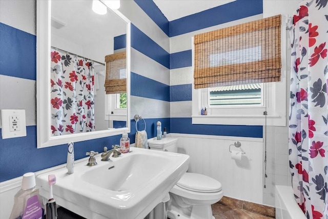 5012 Eastchester Dr, Sarasota, FL 34234 - bathroom featuring toilet, tile patterned floors, a sink, and a wainscoted wall