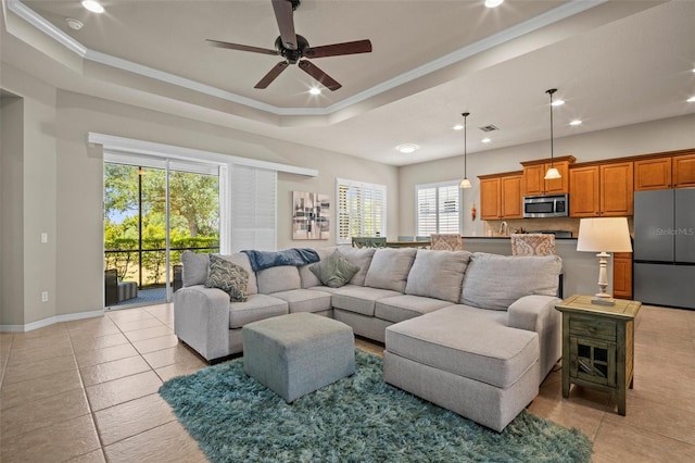 living area featuring crown molding, a raised ceiling, ceiling fan, and light tile patterned floors