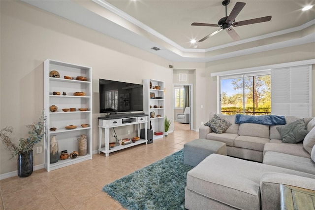 living room featuring tile patterned floors, a ceiling fan, baseboards, visible vents, and ornamental molding