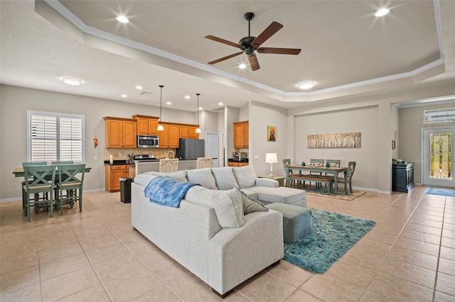 living area with a healthy amount of sunlight, light tile patterned floors, a ceiling fan, and a tray ceiling
