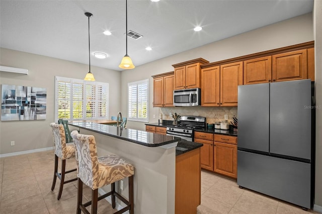 kitchen featuring visible vents, a kitchen breakfast bar, brown cabinets, tasteful backsplash, and appliances with stainless steel finishes