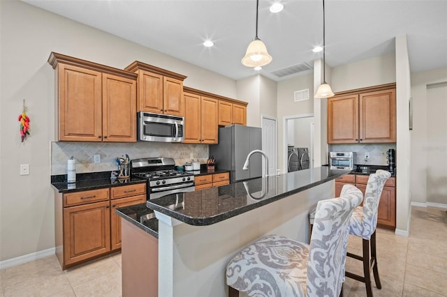 kitchen featuring a breakfast bar area, baseboards, appliances with stainless steel finishes, and washer and clothes dryer