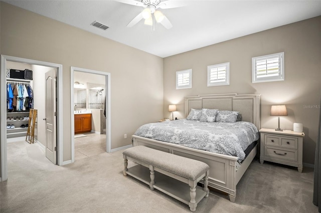 bedroom with visible vents, baseboards, a spacious closet, light carpet, and ensuite bath
