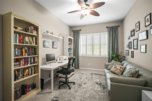 carpeted office space featuring baseboards and ceiling fan