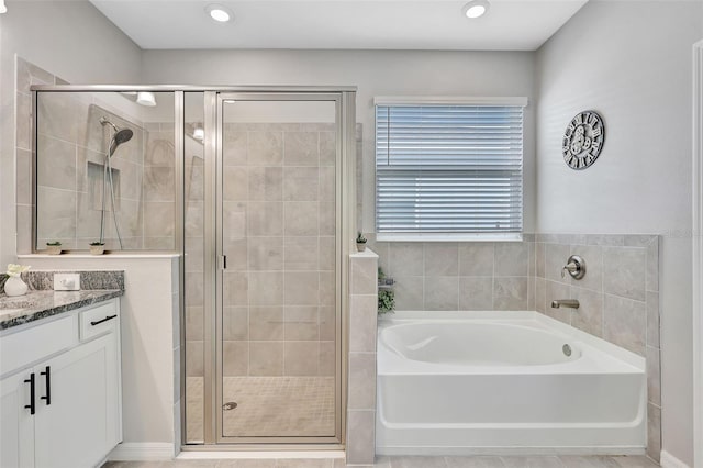 bathroom with a stall shower, vanity, and a bath