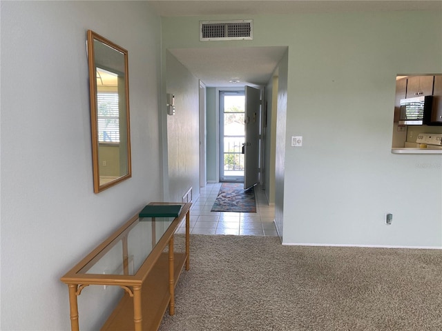 hall with light carpet, light tile patterned floors, and baseboards