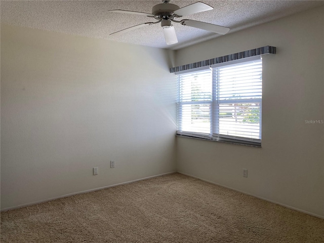 unfurnished room with a textured ceiling, carpet floors, a ceiling fan, and baseboards