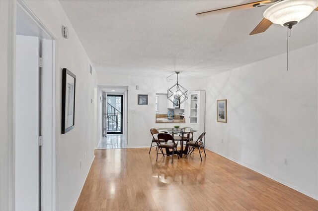 2280 Stickney Point Rd Unit 420, Sarasota, FL 34231 - dining room featuring baseboards, a ceiling fan, a textured ceiling, and light wood-style flooring