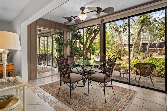 sunroom featuring outdoor dining area, a ceiling fan, plenty of natural light, and tile patterned floors