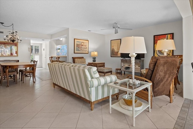living area with a textured ceiling, light tile patterned flooring, and ceiling fan with notable chandelier