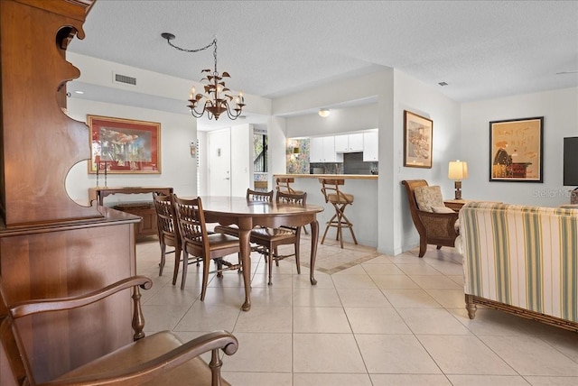 dining area with a textured ceiling, light tile patterned flooring, visible vents, an inviting chandelier, and baseboards