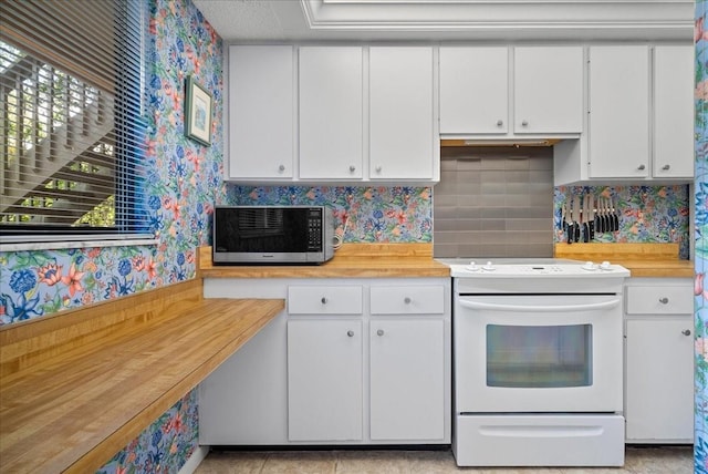 kitchen with stainless steel microwave, white electric range oven, decorative backsplash, white cabinetry, and wallpapered walls