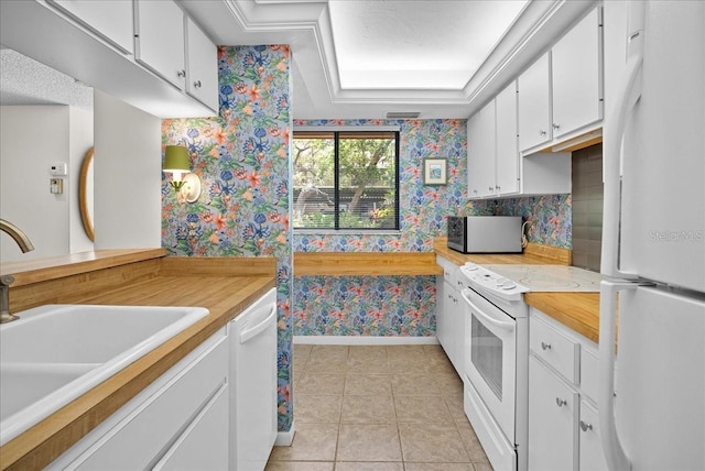 kitchen featuring a sink, white appliances, white cabinetry, light countertops, and wallpapered walls