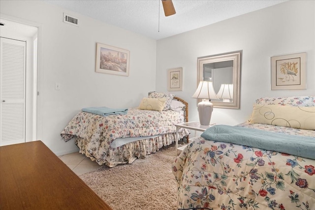 bedroom featuring tile patterned flooring, a textured ceiling, ceiling fan, and visible vents