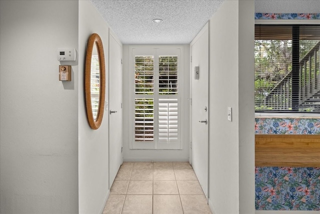 doorway with light tile patterned floors and a textured ceiling