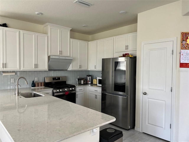 5521 Summit Gln, Bradenton, FL 34203 - kitchen featuring appliances with stainless steel finishes, under cabinet range hood, a sink, a peninsula, and white cabinetry