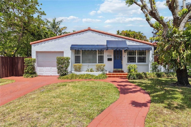mediterranean / spanish-style home featuring fence, a front yard, stucco siding, an attached garage, and driveway