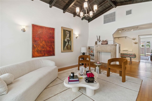 living area with a fireplace, a chandelier, beamed ceiling, visible vents, and hardwood / wood-style flooring