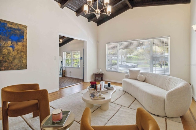living room featuring baseboards, beamed ceiling, a notable chandelier, and wood finished floors