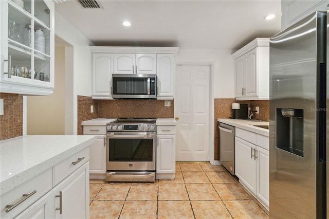 kitchen with backsplash, visible vents, white cabinets, glass insert cabinets, and stainless steel appliances