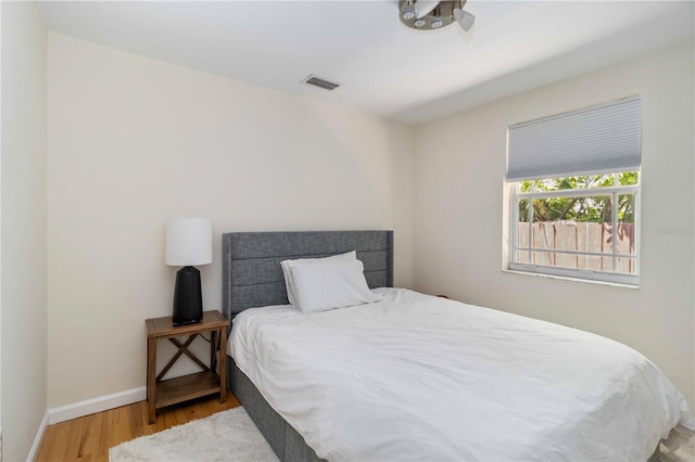 bedroom featuring visible vents, baseboards, and wood finished floors