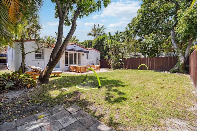 view of yard with outdoor lounge area, french doors, a fenced backyard, and a patio area