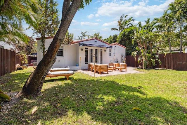 rear view of property with a yard, french doors, a fenced backyard, and stucco siding