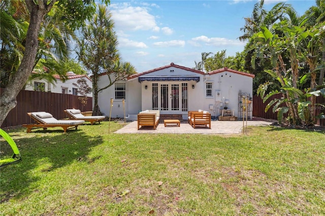 back of property featuring a fenced backyard, french doors, an outdoor hangout area, a patio area, and a lawn