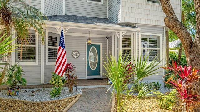 property entrance featuring a porch and roof with shingles