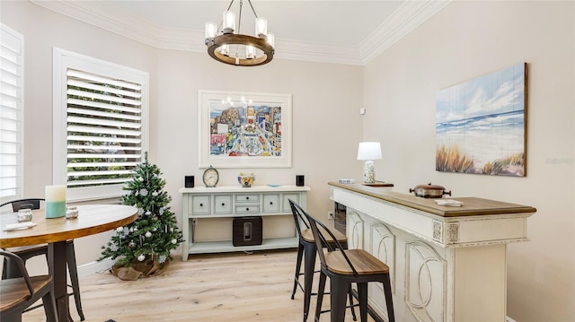 bar featuring light wood finished floors, hanging light fixtures, baseboards, a chandelier, and ornamental molding