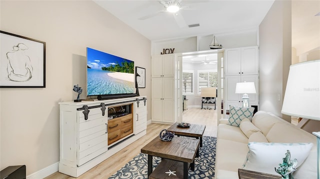 living area with baseboards, light wood-style floors, visible vents, and ceiling fan