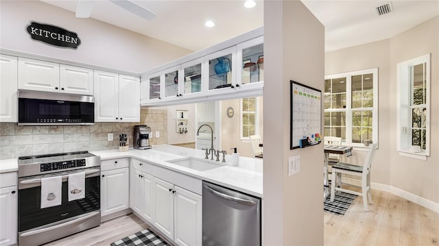 kitchen with light wood finished floors, stainless steel appliances, visible vents, and a sink
