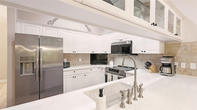 kitchen featuring glass insert cabinets, white cabinetry, stainless steel appliances, and backsplash