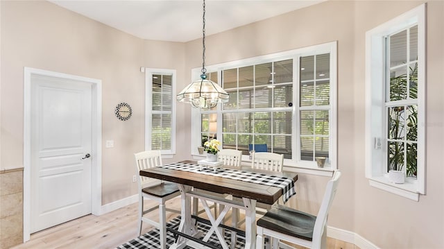 dining space with baseboards, an inviting chandelier, and light wood-type flooring