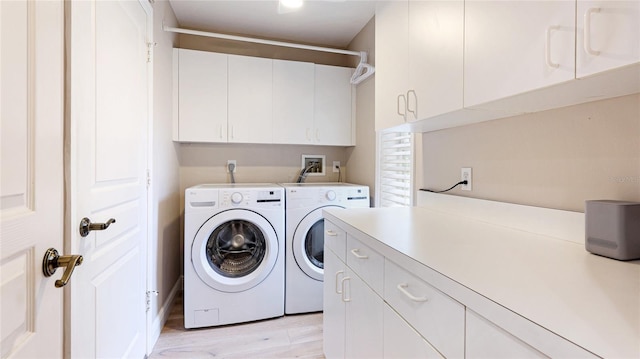 washroom featuring separate washer and dryer, cabinet space, and light wood-style floors
